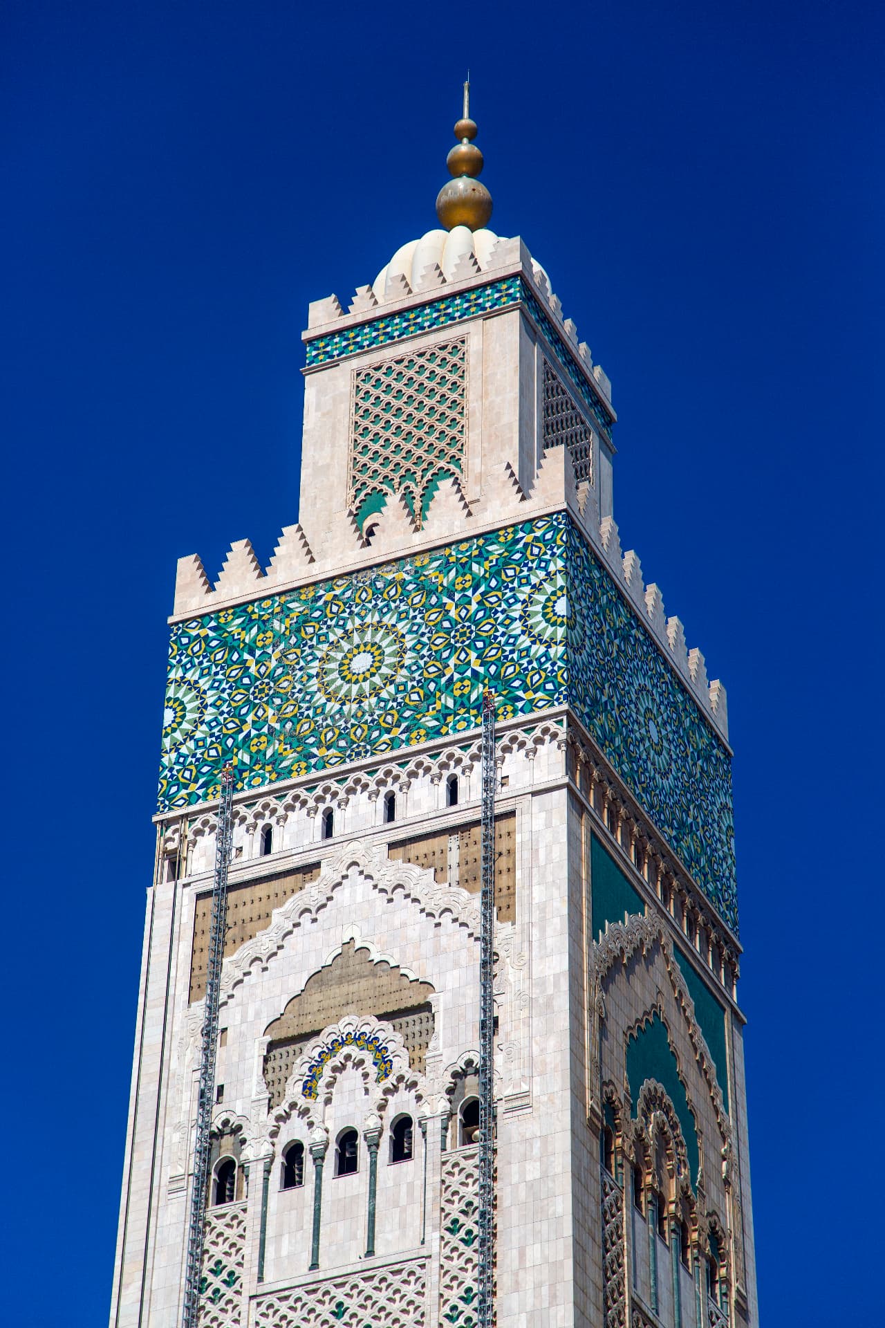 Tiled minaret of the Hassan II Mosque against a deep blue sky