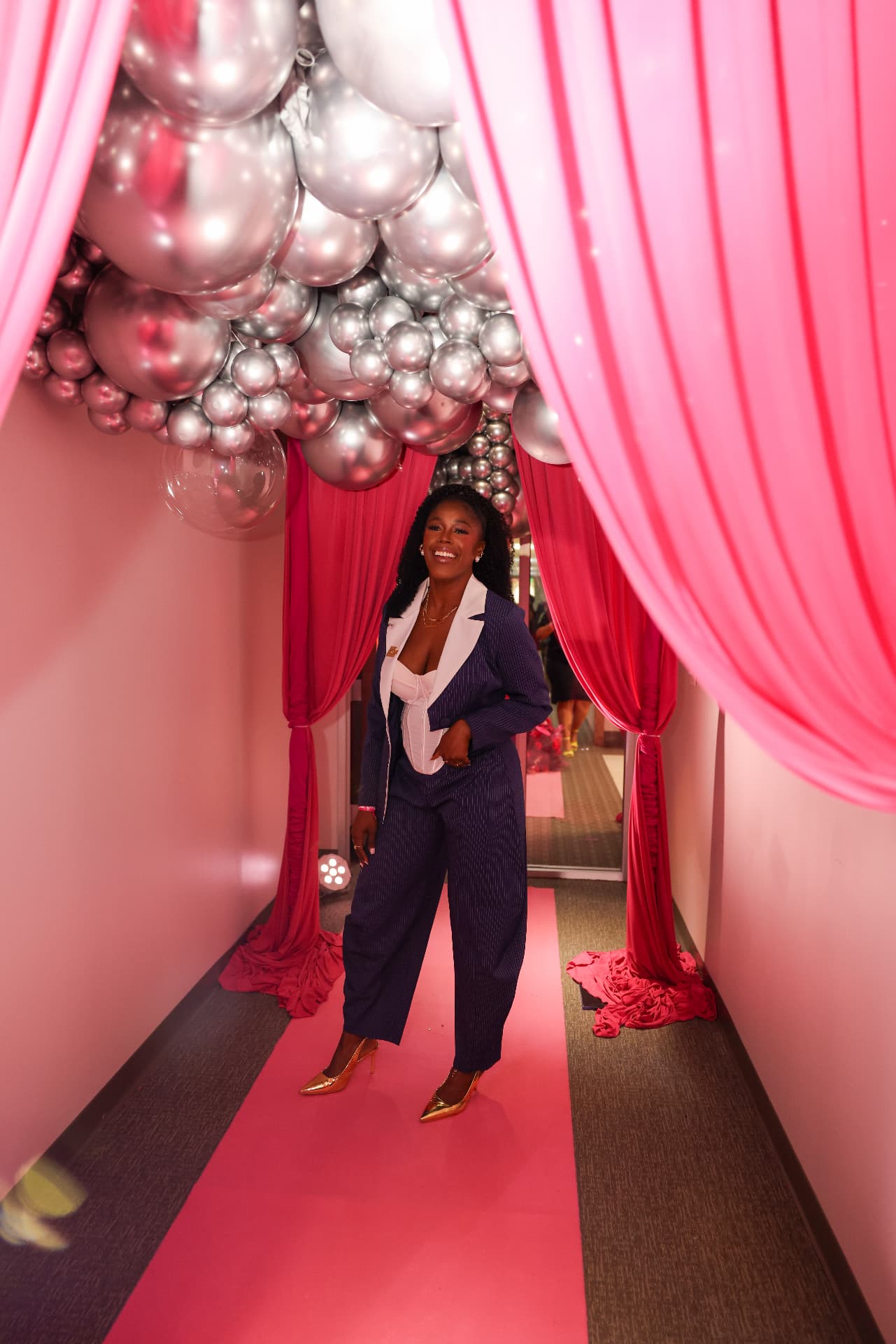 Guest under a silver balloon and pink drape entrance
