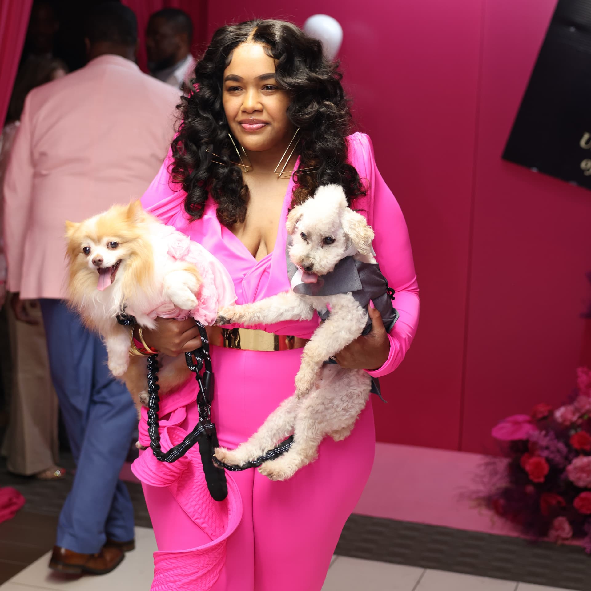 Guest in hot pink holding two small dogs