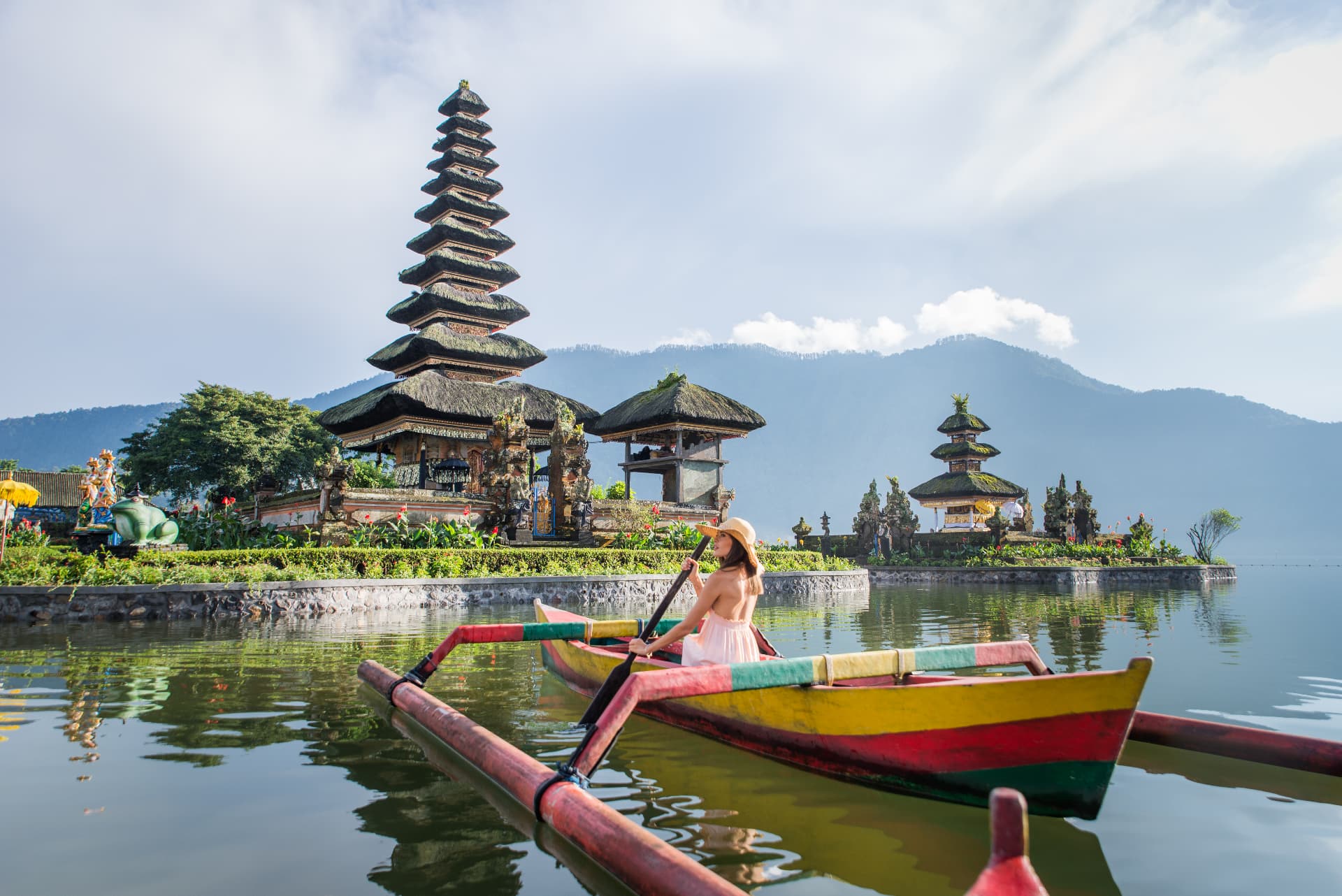 Woman rowing a boat near a Balinese lake temple